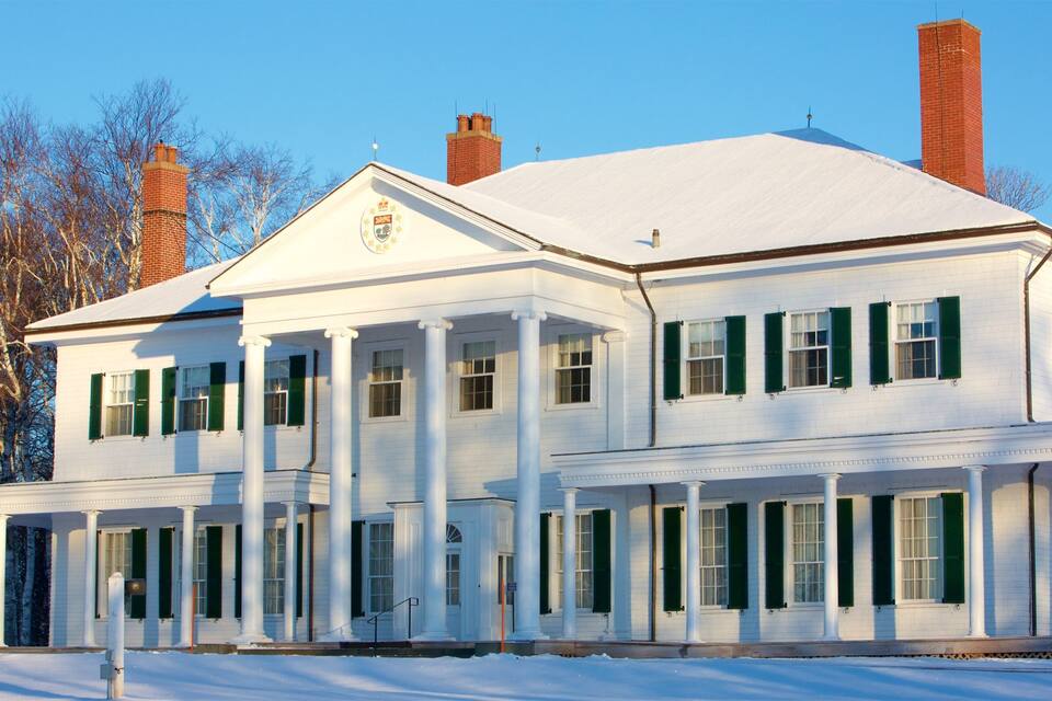 A large white building with green shutters, columns, and chimneys.