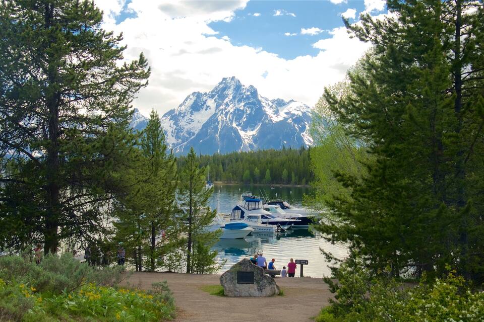 A lake with boats, a rocky outcrop, and snow-capped mountains in the background.