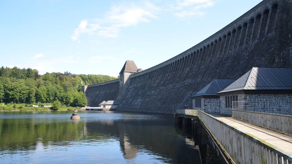 A large dam with a wooden walkway alongside a calm river.