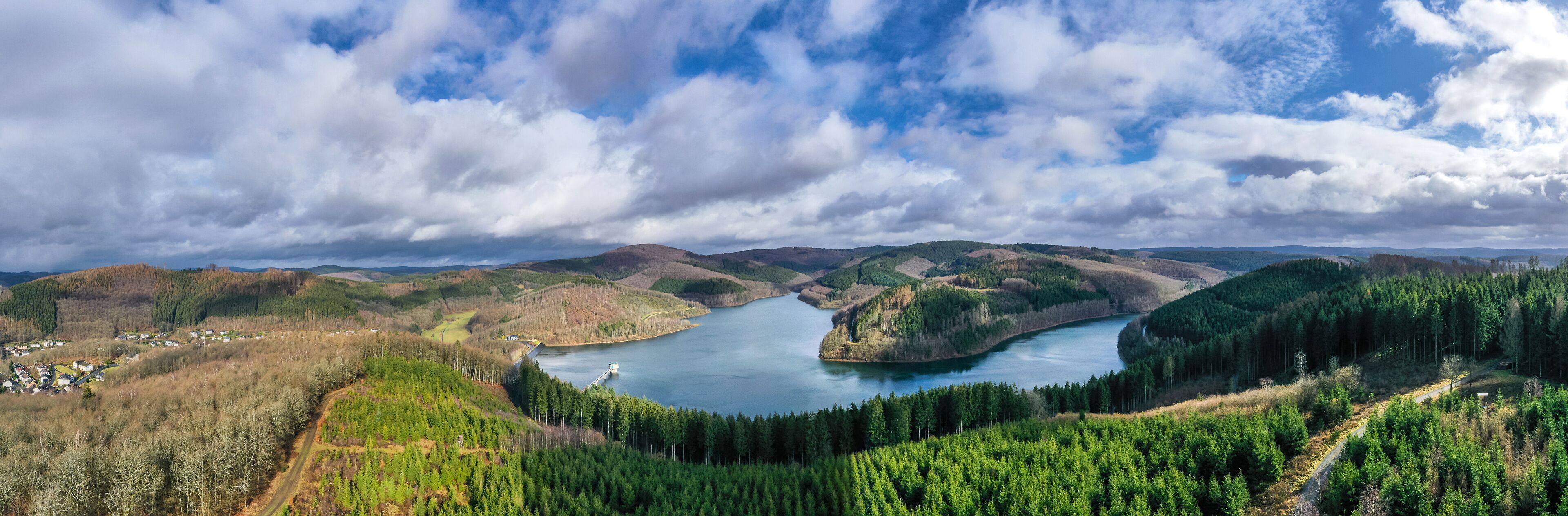 A river winding through a forested valley with hills in the background.