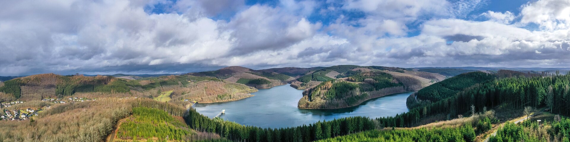 A river winding through a forested valley with hills in the background.