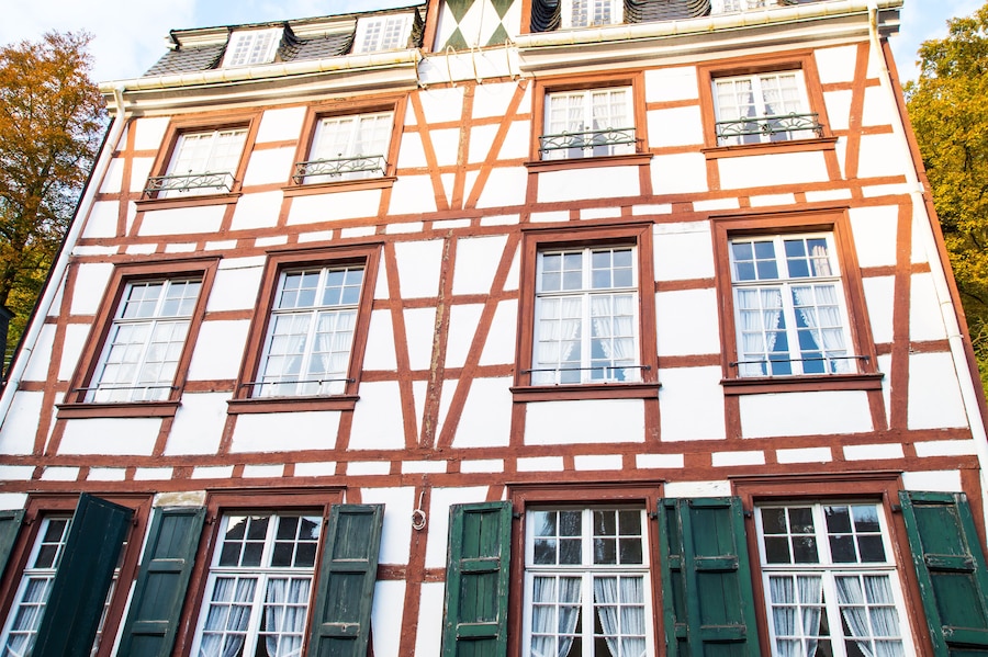 Un edificio tradicional con entramado de madera, múltiples ventanas y contraventanas verdes.