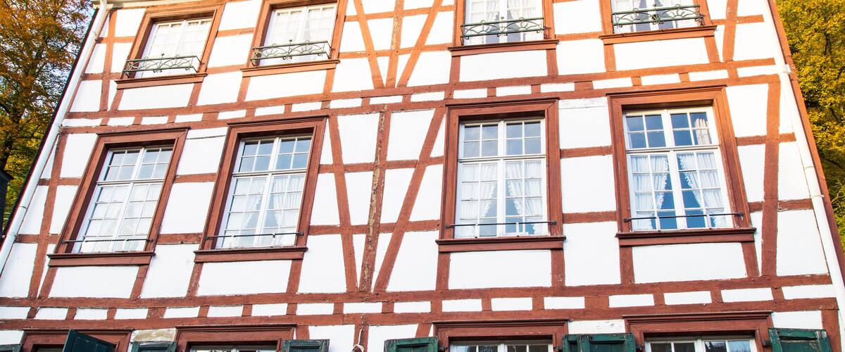 A traditional half-timbered building with multiple windows and green shutters.