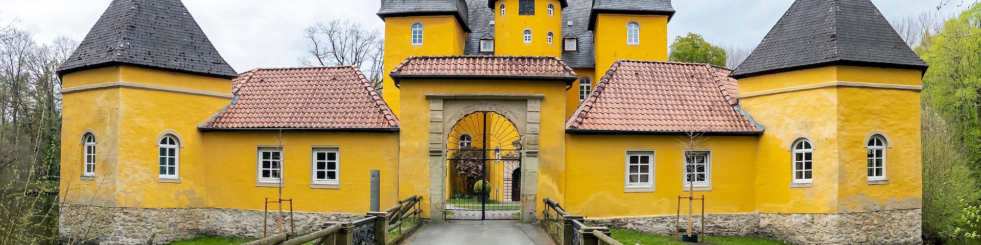 A yellow castle with three towers and a central archway.