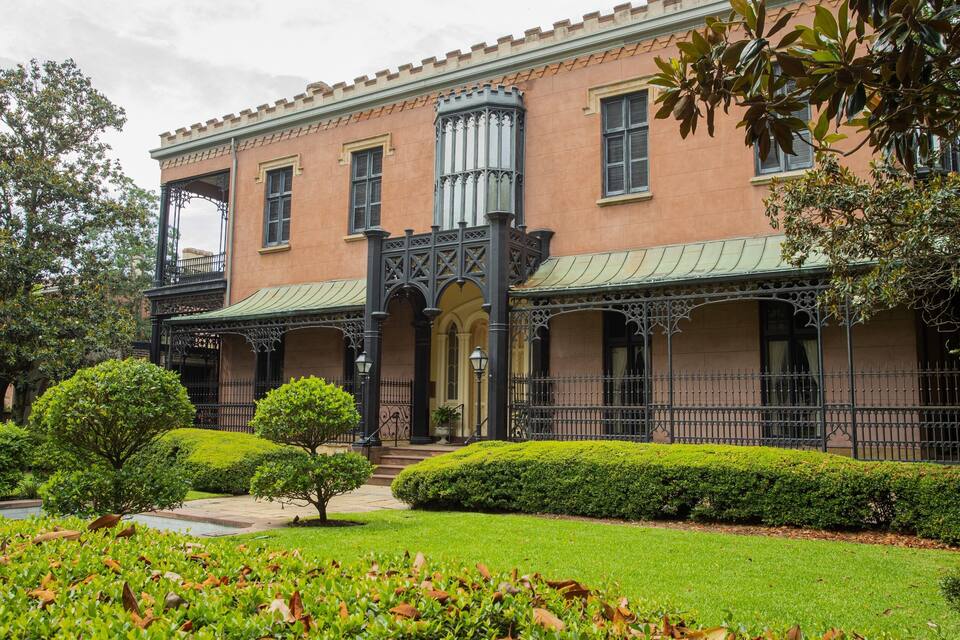 Edifici històric amb reixa ornamental, teulada verda i jardins ben cuidats.