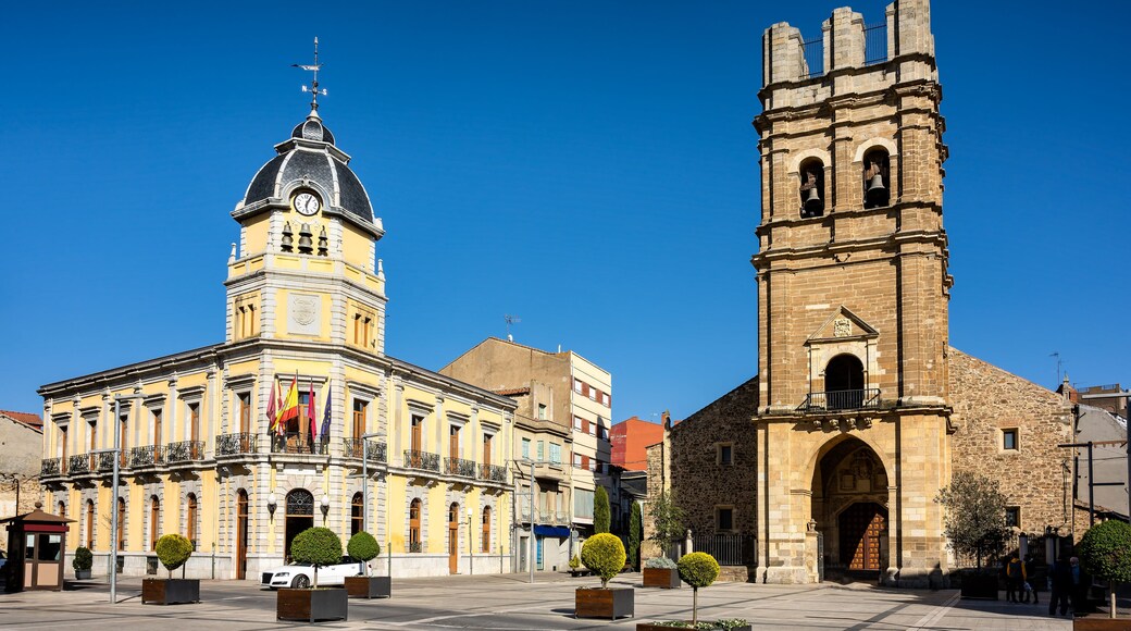 Cityscape of old town La Bañeza in Castile and Leon, Spain, with historic town hall building and landmark Saint Mary church on the main town square.