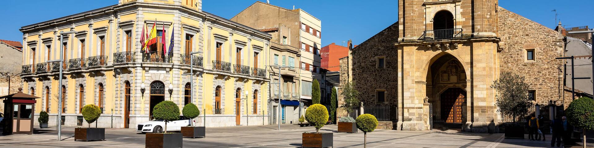 Cityscape of old town La Bañeza in Castile and Leon, Spain, with historic town hall building and landmark Saint Mary church on the main town square.