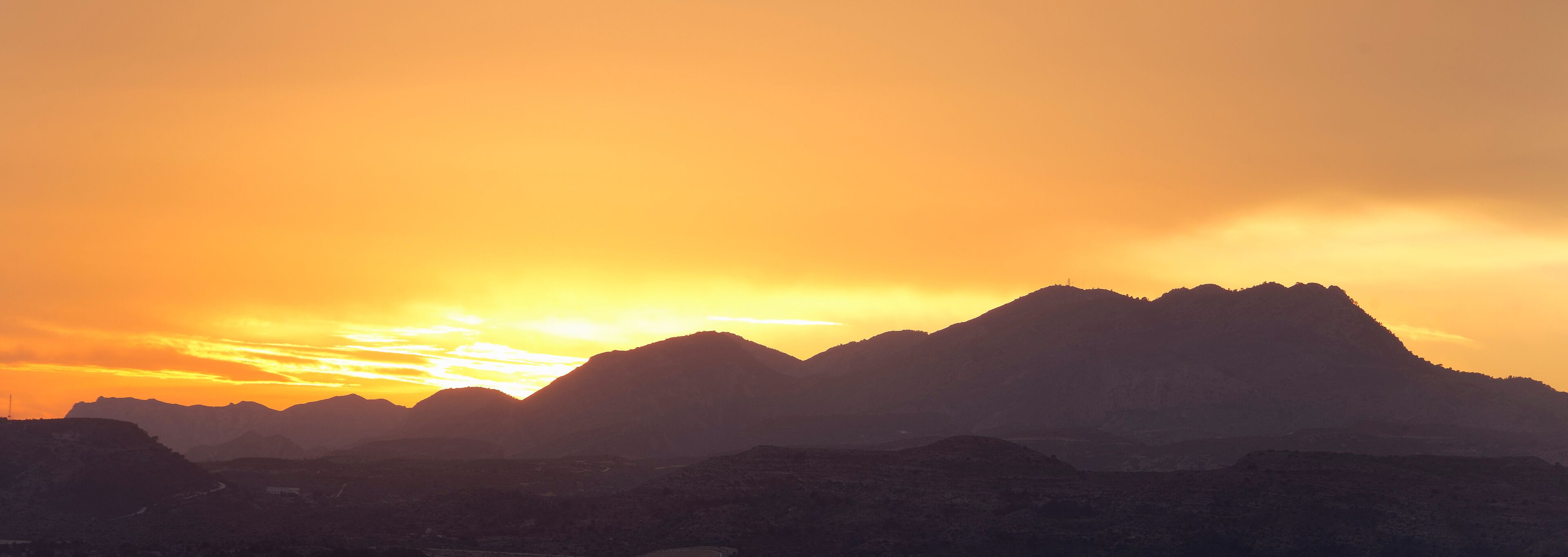 A mountain range silhouetted against a sunset sky.
