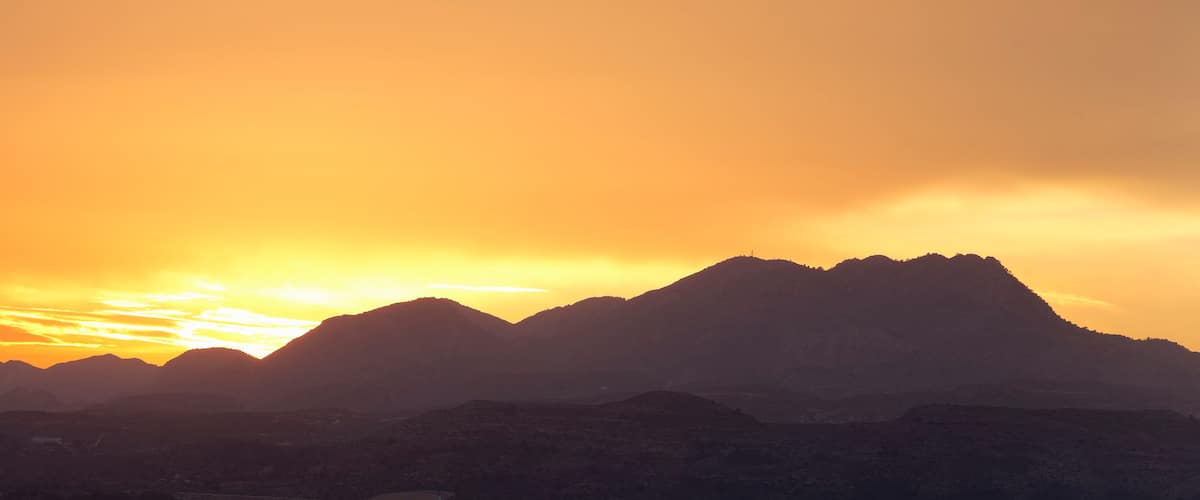 A mountain range silhouetted against a sunset sky.