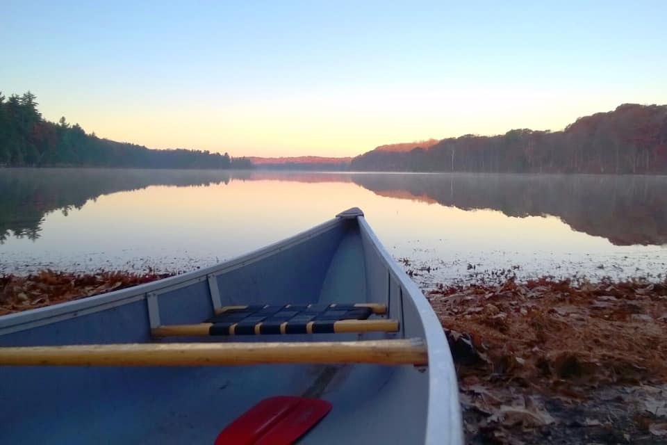 A canoe on a calm lake with a forested shoreline.