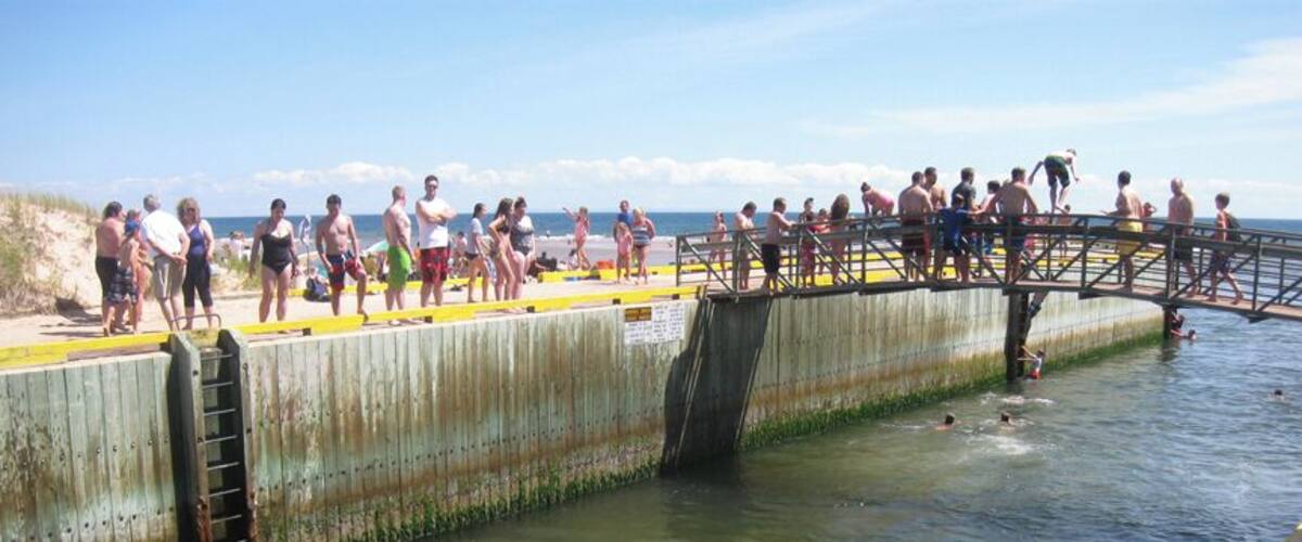 A pier with people swimming and standing on it.
