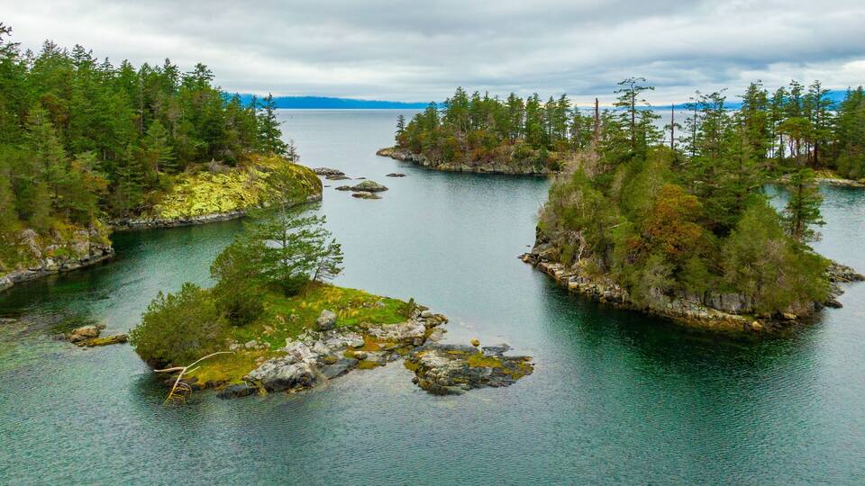 A calm lake surrounded by dense forests and rocky islands.