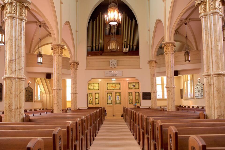 Interior d'una església amb columnes de marbre, pews de fusta, vidrieres i un òrgan gran.