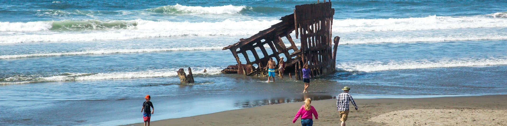 Hammond, Oregon; Tourists inspecting the remains of the wreck of the sailing ship, the Peter Iredale, on the beach at Fort Stephens State park in Oregon.
