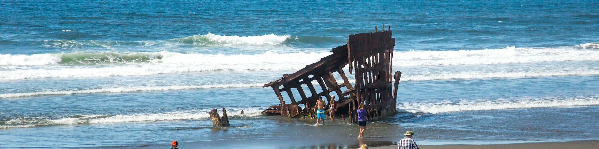 Hammond, Oregon; Tourists inspecting the remains of the wreck of the sailing ship, the Peter Iredale, on the beach at Fort Stephens State park in Oregon.