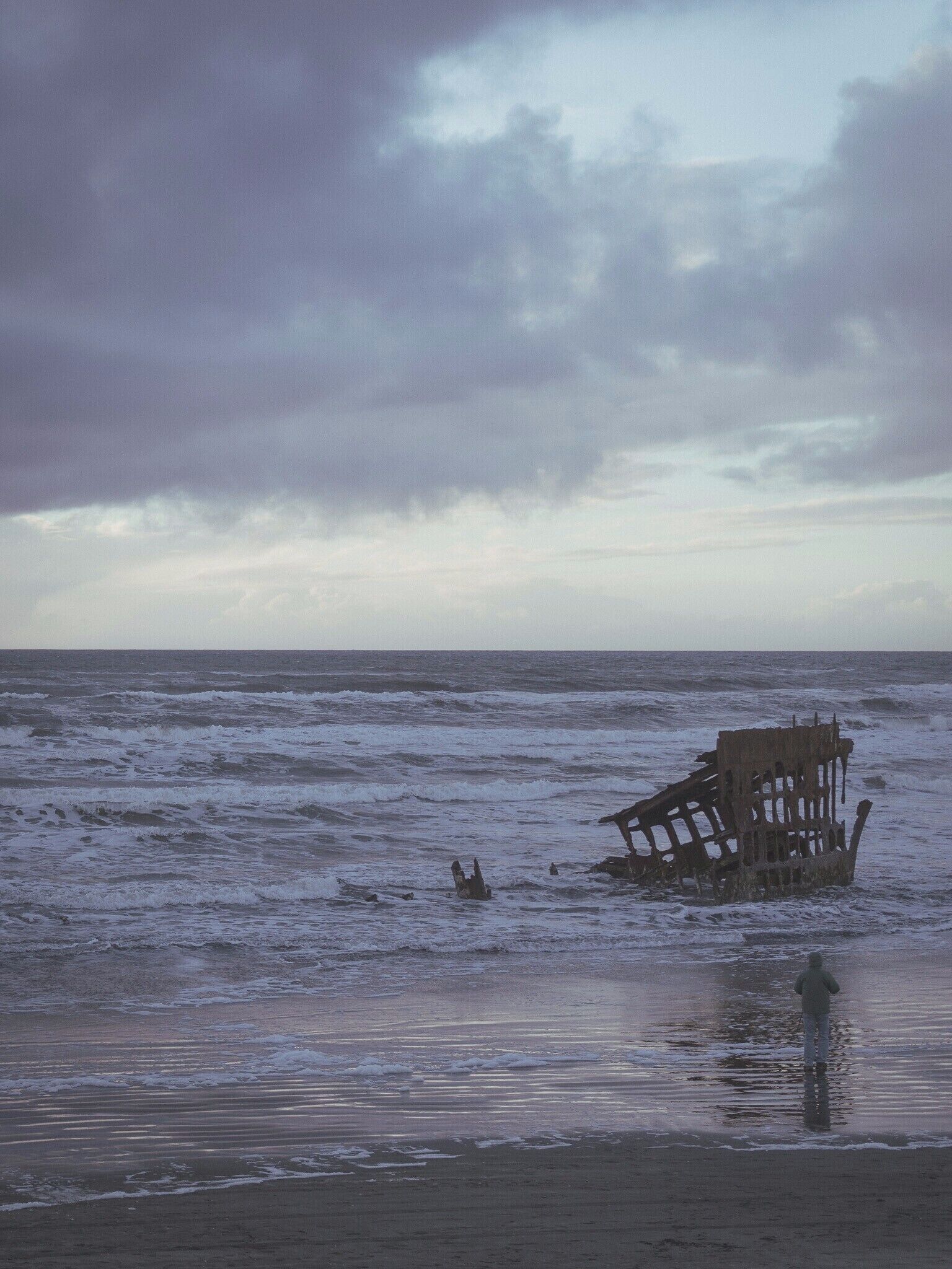 A shipwreck in the ocean with waves crashing around it.