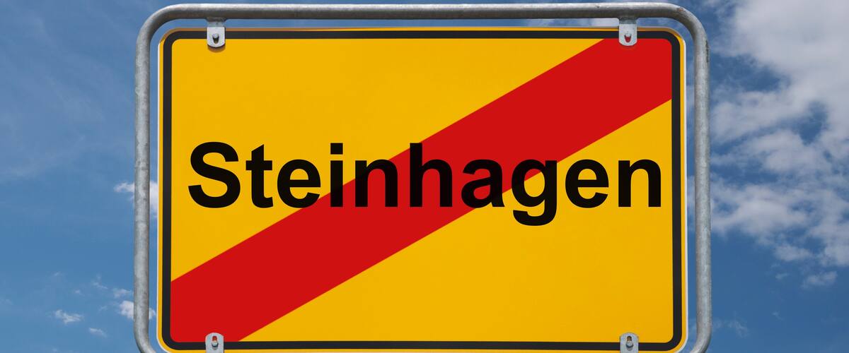 A road sign with the word "Steinhagen" on a yellow background with a red diagonal stripe.