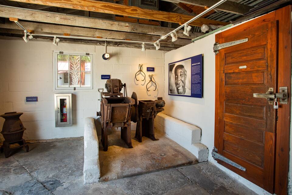 A historical exhibit with antique ice chippers, a vintage ice maker, and a wooden door.