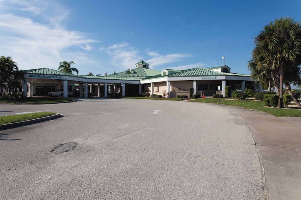 A building with a green roof and a sign that reads "Cocoa Beach Country Club".