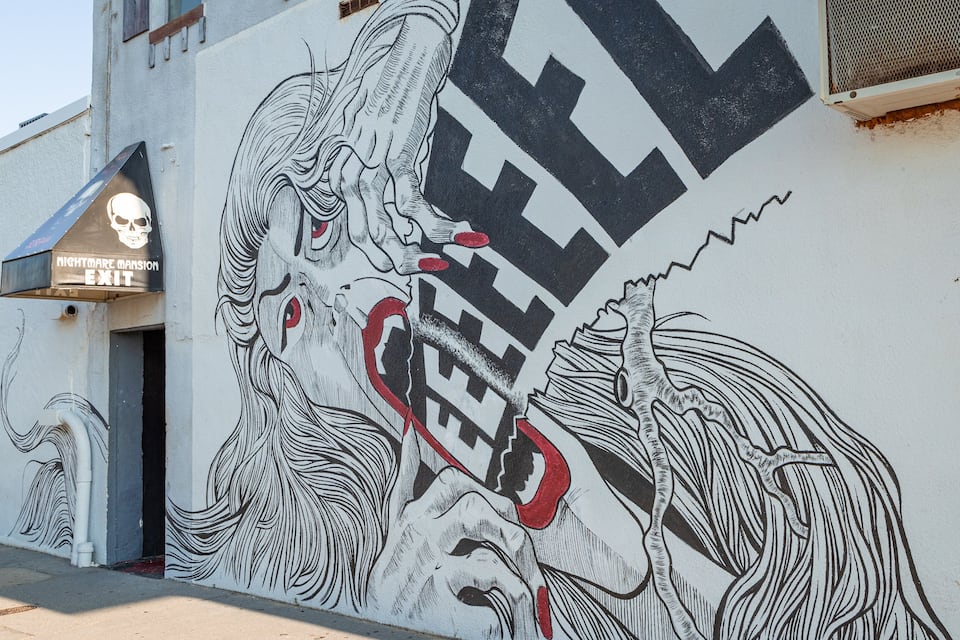 Edifici amb un mural d'una dona i un home, i un rètol que diu "NIGHTMARE MASSION EXIT".