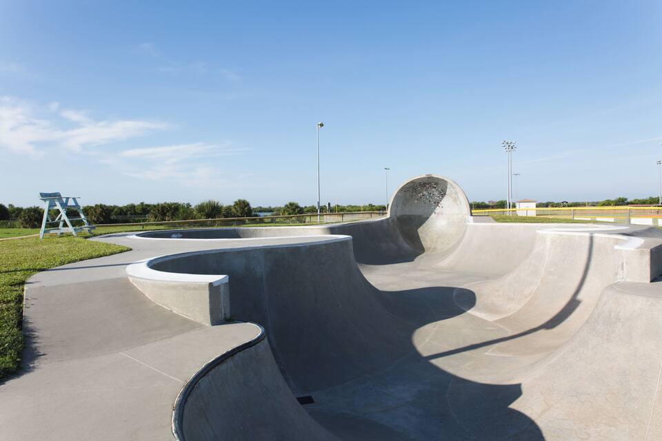 Un skatepark amb rampes de formigó i una cadira blava.