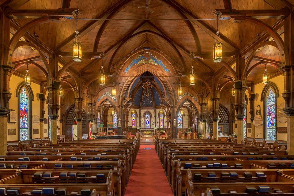 Interior de iglesia con bancos de madera y vidrieras.