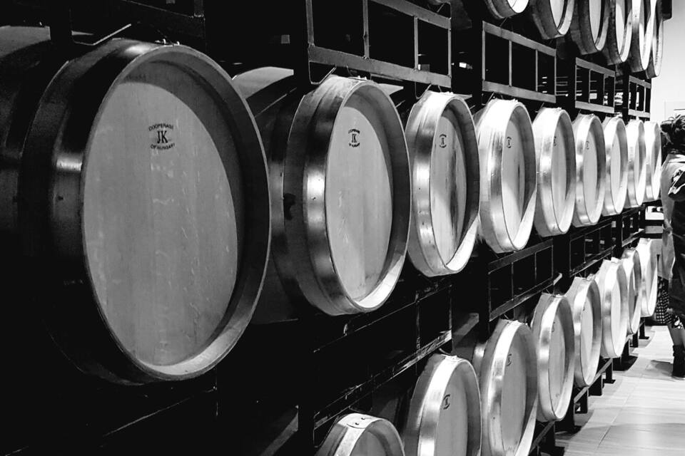 Une rangée de barriques de vin dans un entrepôt.