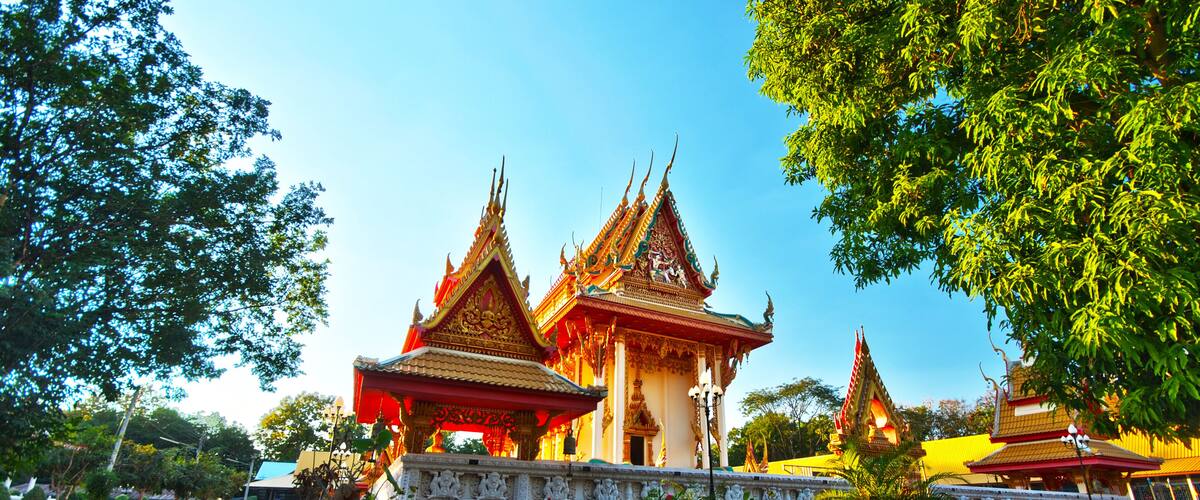 A traditional Thai temple with ornate architecture and a well-maintained garden.