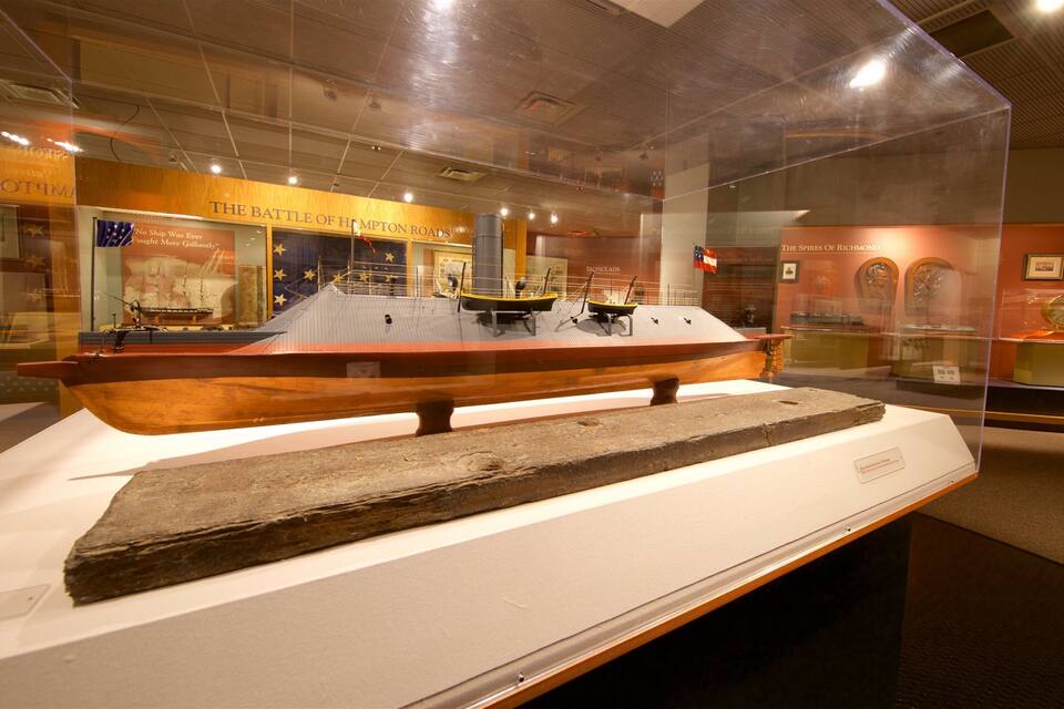 A museum exhibit with a large wooden ship model and a stone artifact on display.