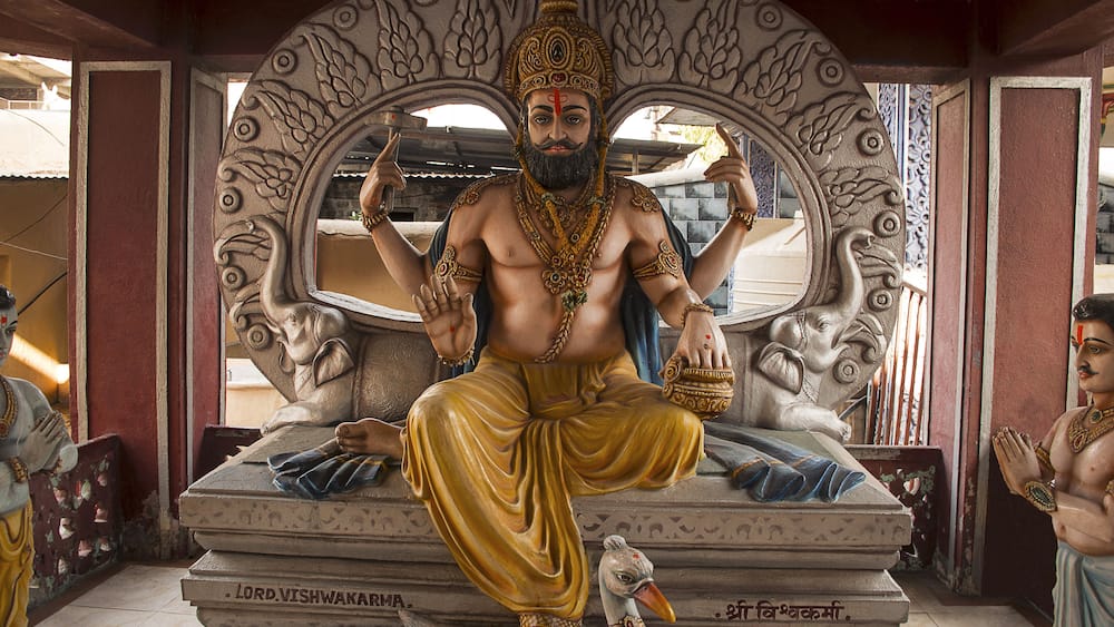 A statue of a deity with multiple arms, seated on a pedestal with inscriptions.