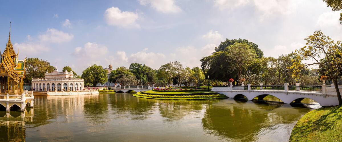 A river with a bridge, a golden temple, and a white building with a dome.