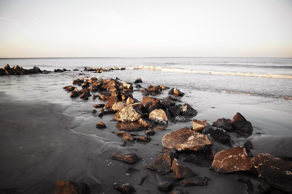 A rocky shoreline with large boulders scattered across the sand.