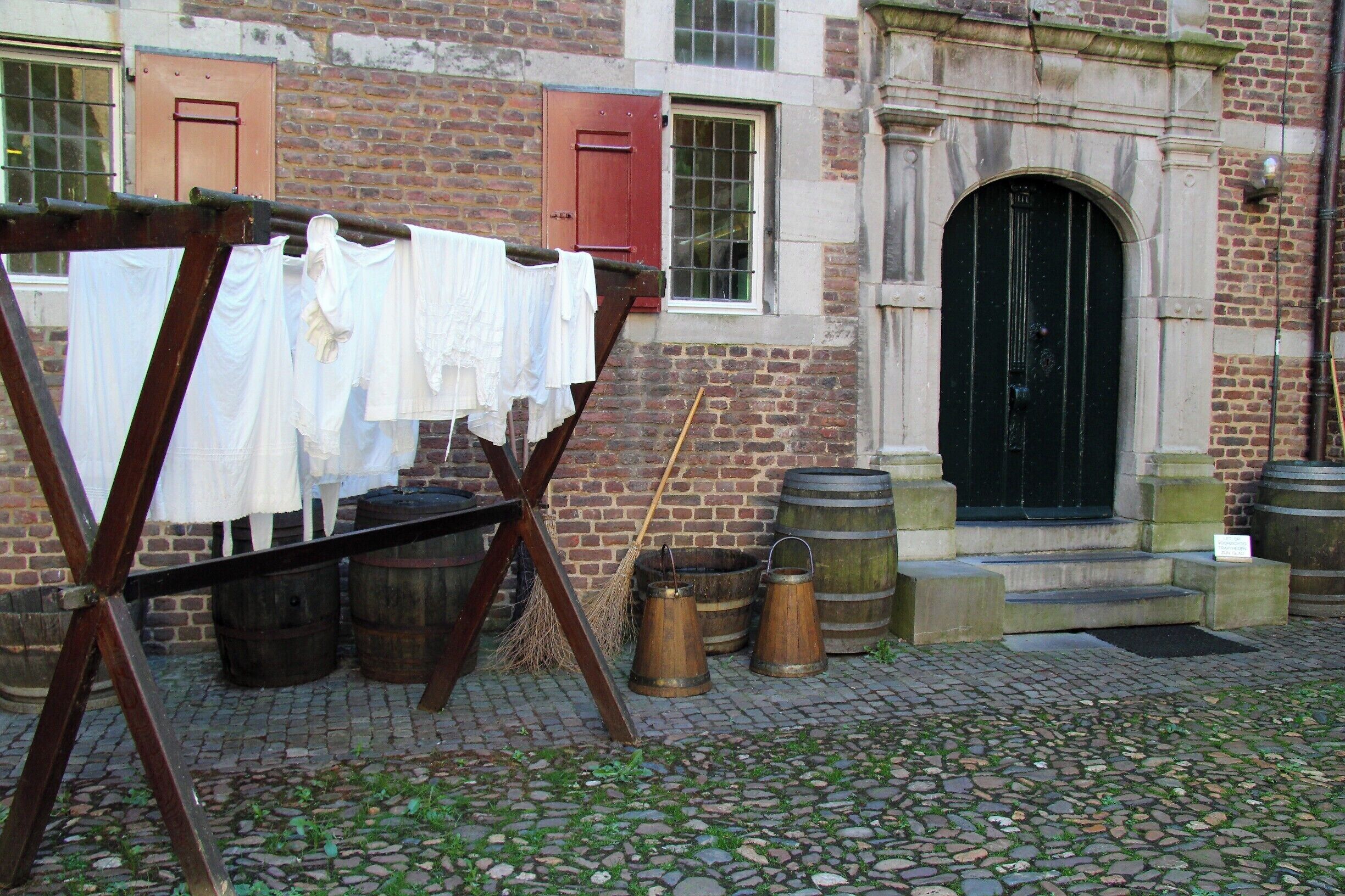 A historic building with a brick facade, a black door, and a clothesline with white garments.