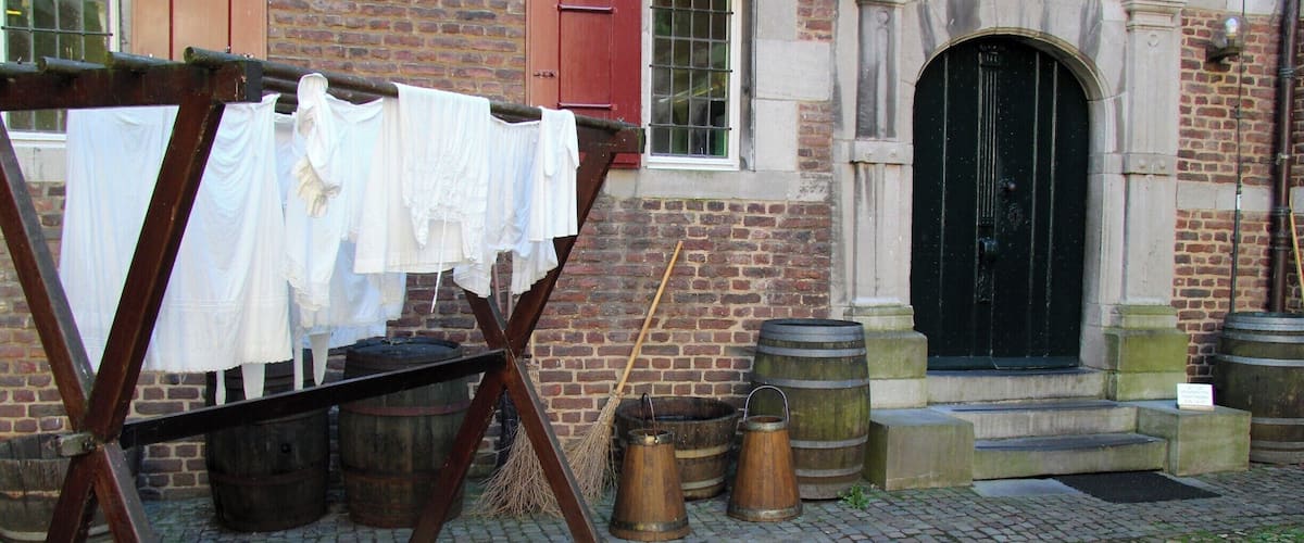 A historic building with a brick facade, a black door, and a clothesline with white garments.