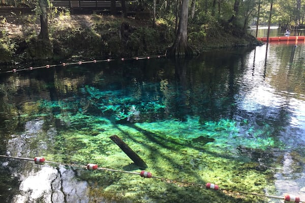 Une rivière aux eaux claires, où l’on peut voir des rochers sous la surface, et une barrière faite de cordes.