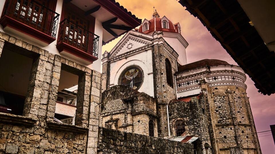 A historic building with a clock tower, stone walls, and traditional wooden balconies.