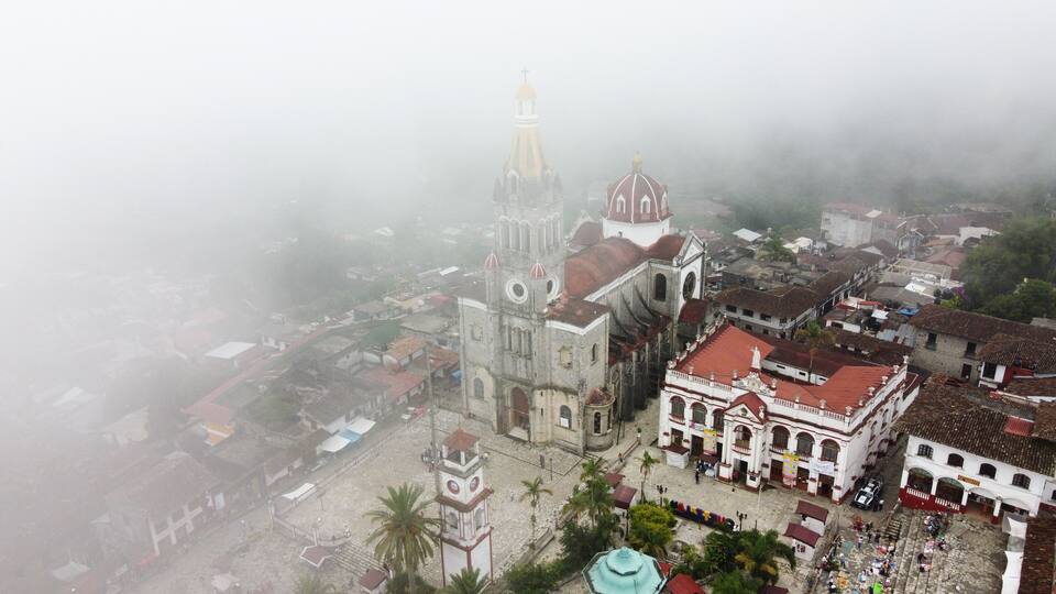 A historic town with a prominent church featuring a tall bell tower and a dome, surrounded by cobblestone streets and traditional buildings.
