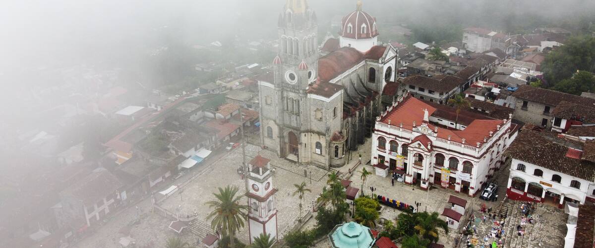 A historic town with a prominent church featuring a tall bell tower and a dome, surrounded by cobblestone streets and traditional buildings.