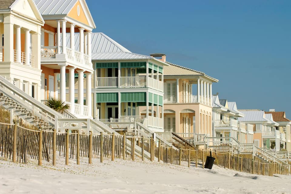 Une rangée de maisons de plage dotées de balcons et d’escaliers menant à la plage.