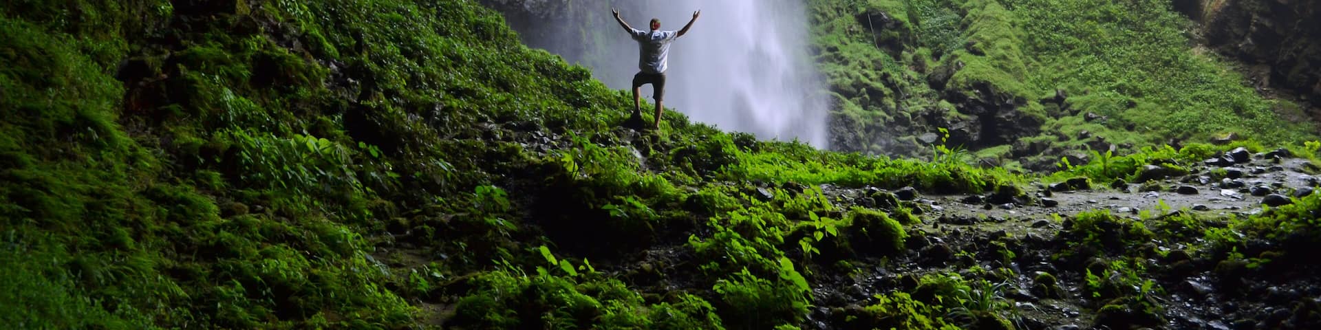Man admiring Puxtla waterfall with arms in the air near Tlatlauquitepec in Mexico