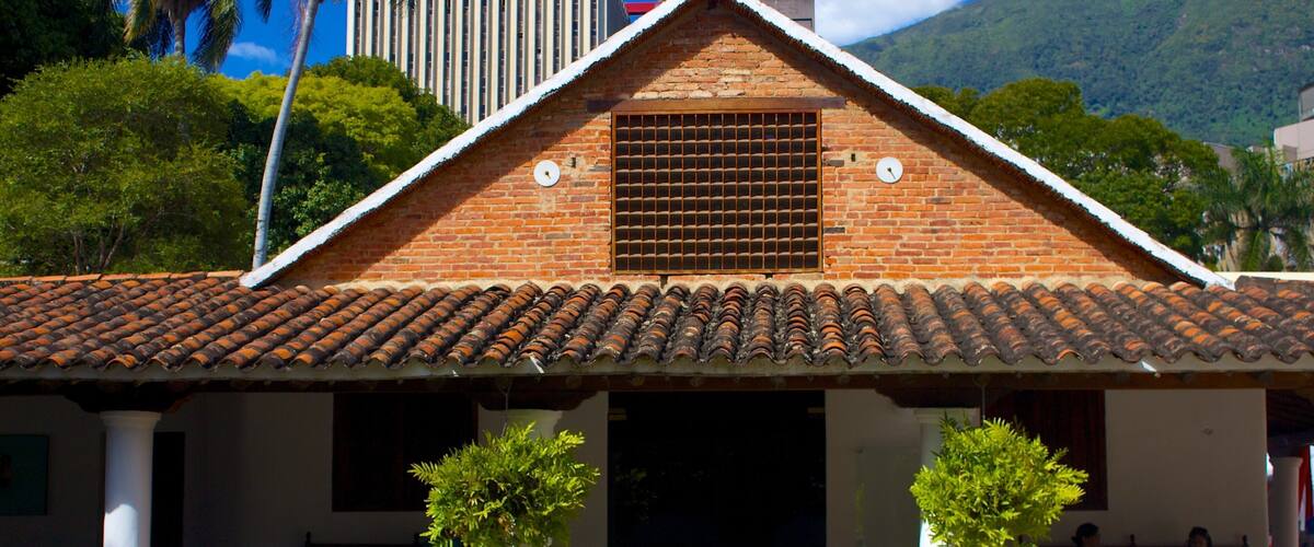 A traditional brick building with a tiled roof, two potted plants, and red flowers in front.