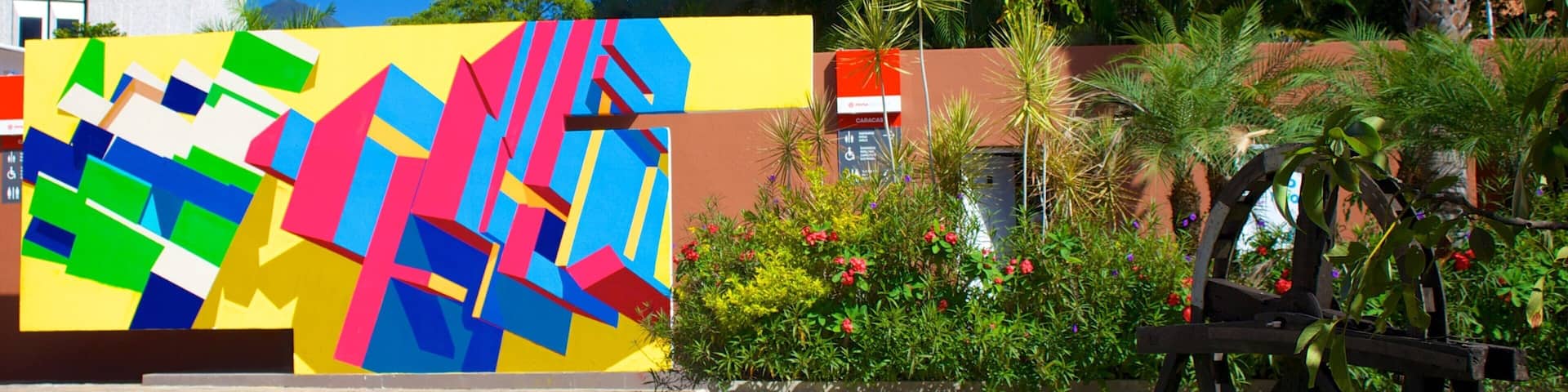 Un mural colorido, un sendero pavimentado y un banco de madera en un parque.