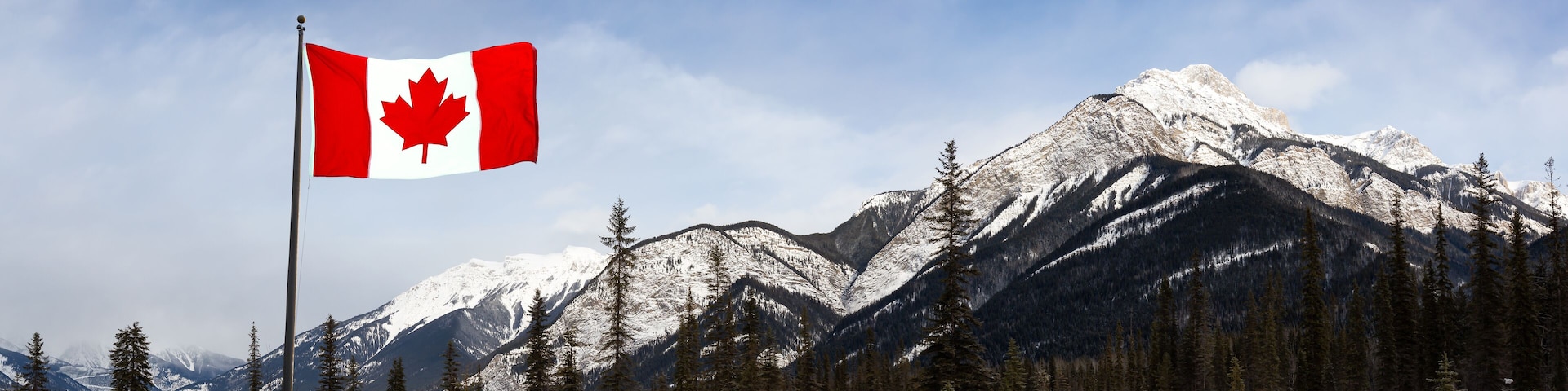 Blaeberry River, near Golden, British Columbia, Canada. Beautiful panoramic Canadian Landscape View of Frozen water and mountains in winter. With Flag Composite