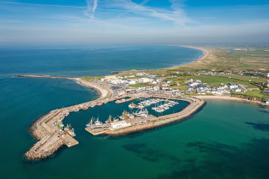 An aerial view of a coastal town with a marina, harbor, and surrounding landscape.