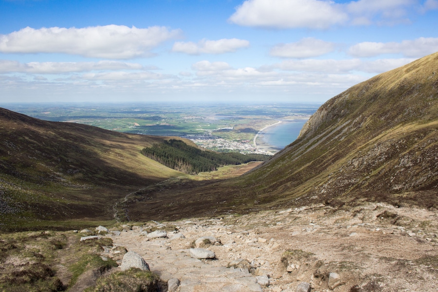 A mountainous landscape with a valley, a river, and a distant town.