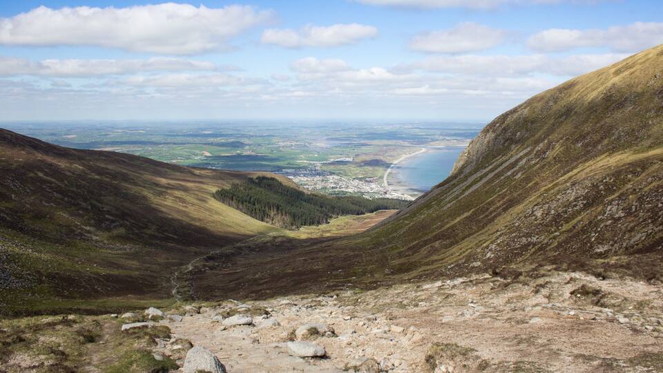 A mountainous landscape with a valley, a river, and a distant town.