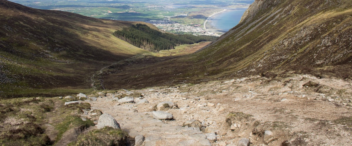 A mountainous landscape with a valley, a river, and a distant town.