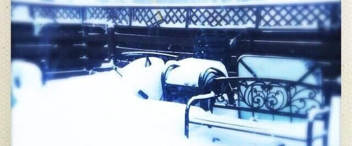 A snow-covered bench with a metal railing.