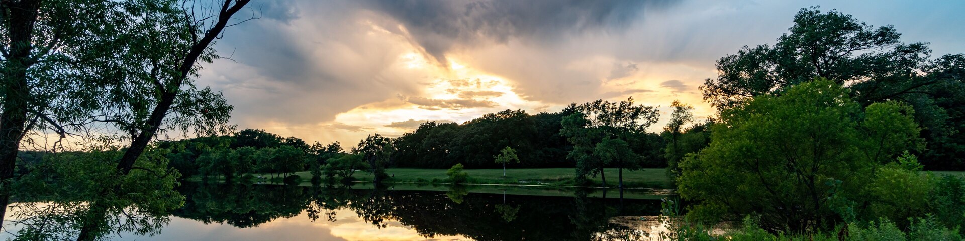 Un lago tranquilo que refleja árboles y un cielo nublado.