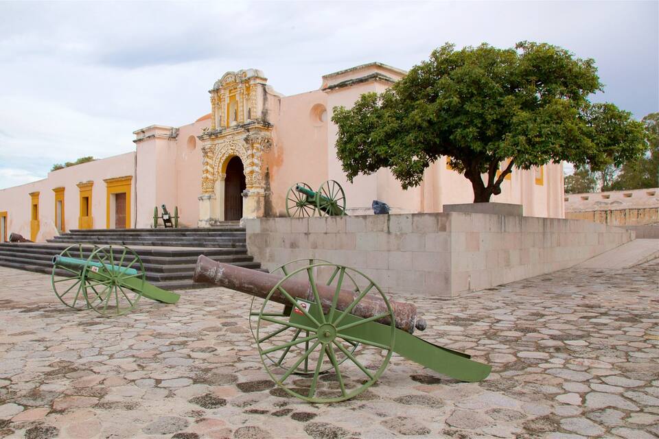 A historic building with ornate architecture, a cobblestone courtyard, and cannons.